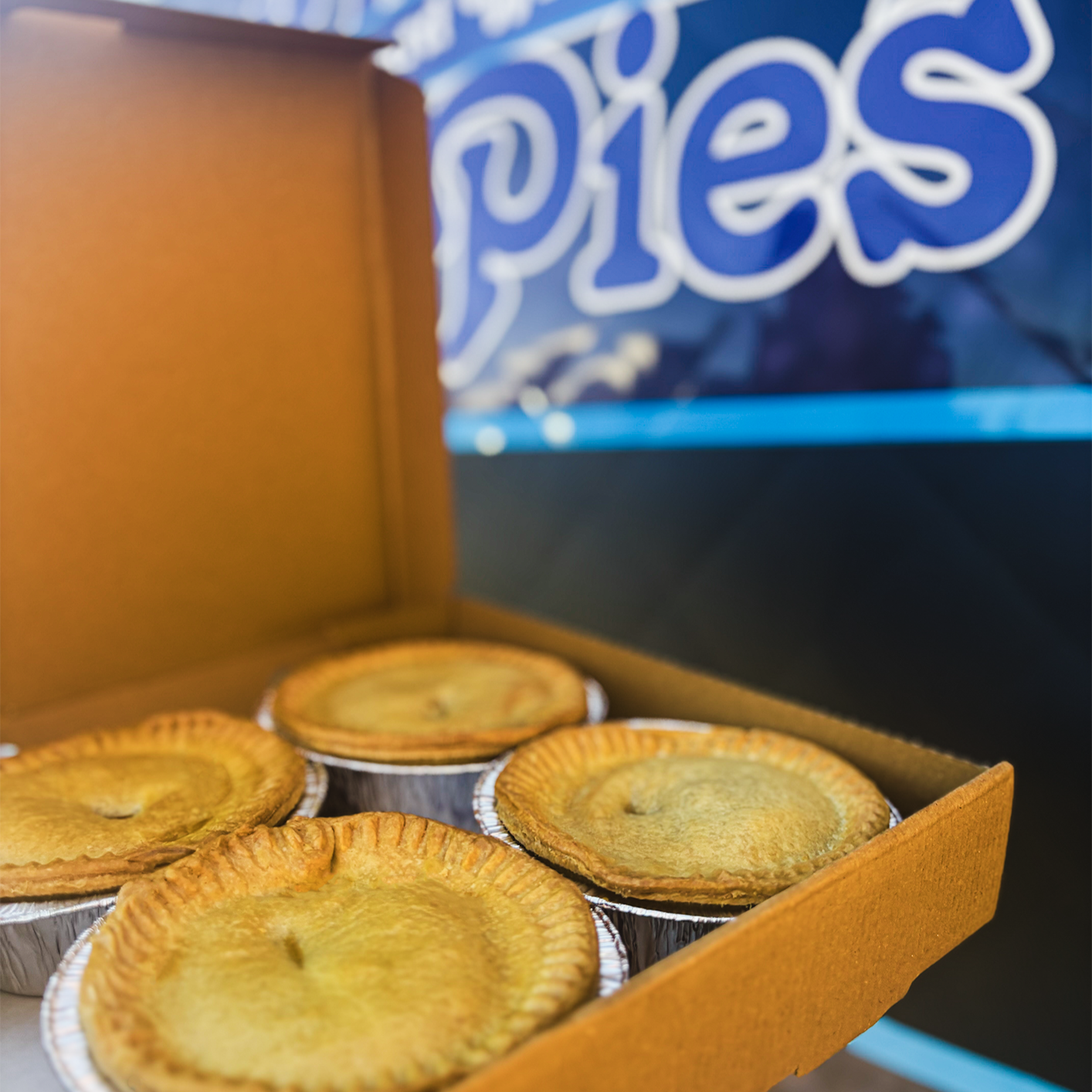Box of meat pies with a Bowen Pies food van in the background. Jiffy vans in the North West.