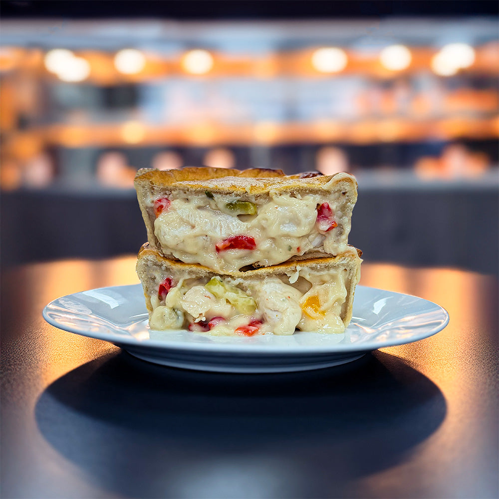 A Salt & Pepper Chicken Pie cut in half on a plate. Ready for pie delivery across the UK.